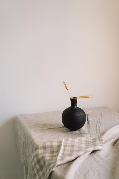 Nowoczesne nakrycie stołu Piękny czarny wazon z lnianą serwetką na stole Tylko naturalne materiały ceramika tekstylia lniane suszone kwiaty