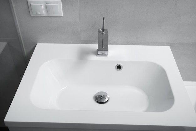 Nowoczesne wnętrze łazienki biała umywalka z szufladami chromowana bateria z gniazdem i włącznikiem na ścianie Wnętrze łazienki z umywalką i kranem