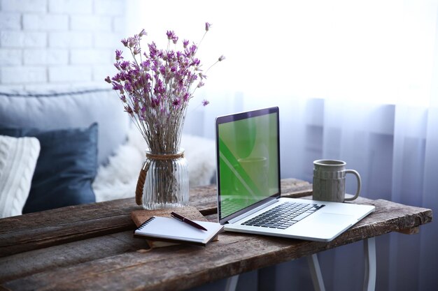 Zdjęcie nowoczesne wnętrze wygodne miejsce pracy drewniany stół z pięknym bukietem kwiatów i laptopem na nim z bliska