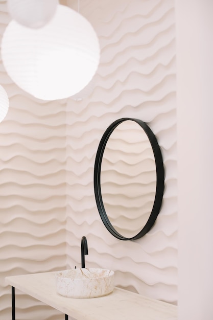 Nowoczesne wnętrze ze stylowym okrągłym lustrem przy beżowej ścianie w przytulnej przestrzeni do kopiowania eleganckich akcesoriów w stylowym wystroju domu