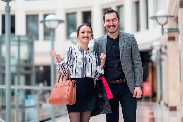 Nowoczesnie wyglądająca uśmiechnięta para w centrum handlowym patrzy w kamerę w radosnym trybie