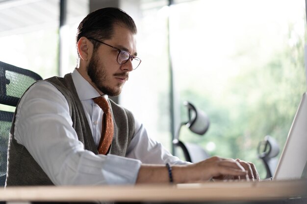 Nowoczesny biznesmen pakietu Office pracujący na komputerze Portret udanego inżyniera oprogramowania Middleaged IT pracującego na komputerze przenośnym