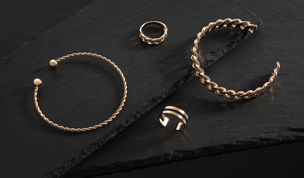 Nowoczesny design Złote błyszczące bransoletki i pierścionki na czarnych kamiennych płytach