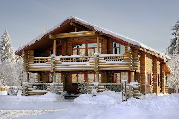 Nowoczesny domek z bali, drewniany dom wakacyjny, zimowy dom drewniany z dużymi oknami, balkonem i werandą.