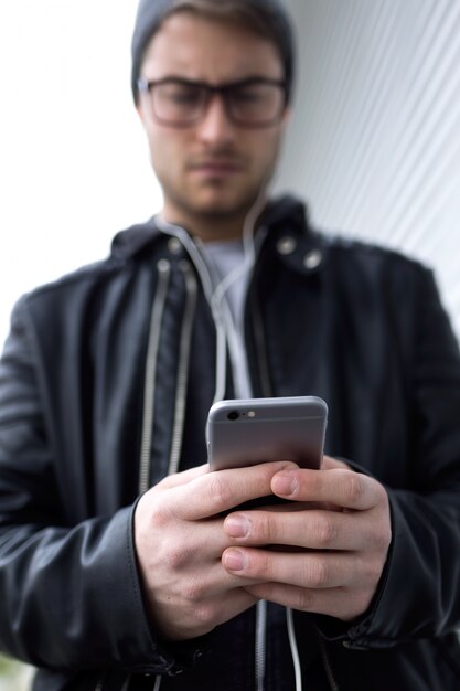 Nowoczesny młody człowiek za pomocą telefonu komórkowego na ulicy.