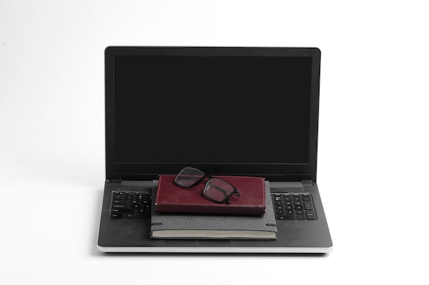 Nowoczesny obszar roboczy z klawiaturą laptopa, notebookiem, okularami na białej powierzchni.