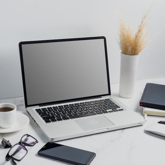Nowoczesny szablon laptopa makiety na białym i czystym biurku z pustym ekranem Biurko w przestrzeni roboczej laptop filiżanka kawy i długopis laptop makieta widok ekranu praca z domu koncepcja
