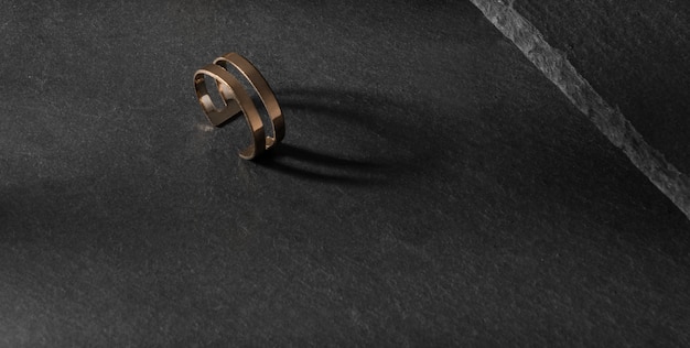 Nowoczesny złoty pierścionek o podwójnym kształcie na ciemnej kamiennej powierzchni z miejscem na kopię copy