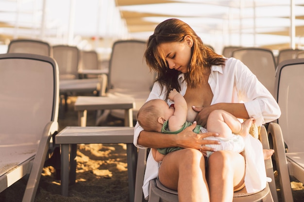 Zdjęcie nowonarodzony chłopiec ssący mleko z piersi matki na plaży