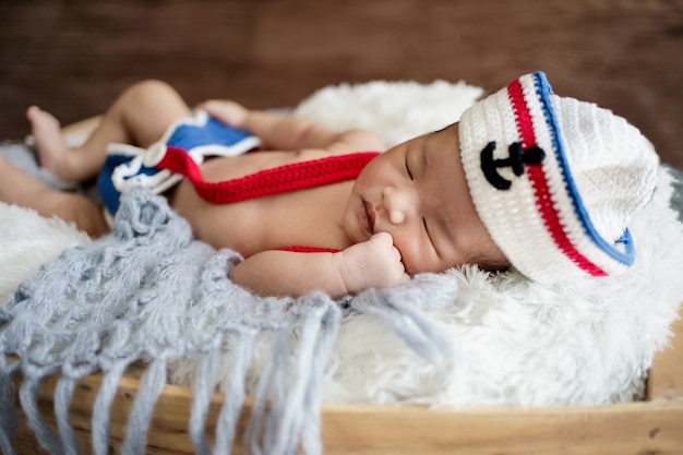 Noworodek chłopiec ubrany w biało-niebieski marynarski kapelusz