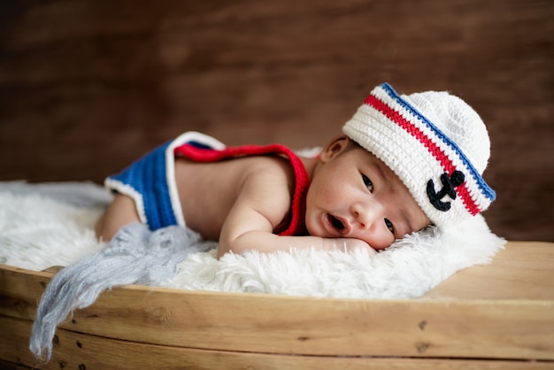 Noworodek chłopiec ubrany w biało-niebieski marynarski kapelusz
