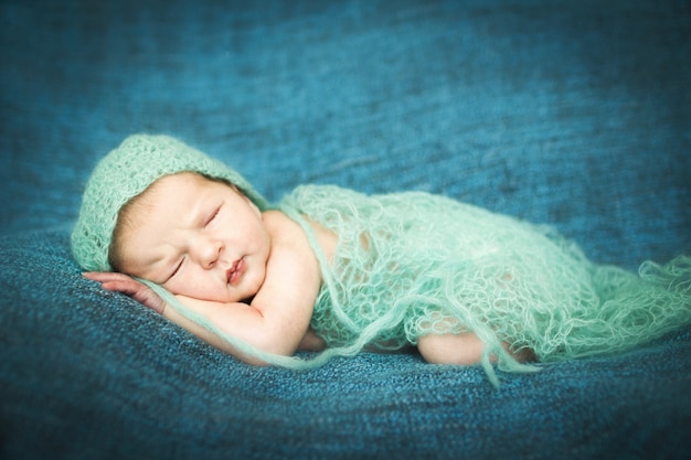 Noworodek śpi słodko na niebieskim dywaniku w niebieskiej czapce