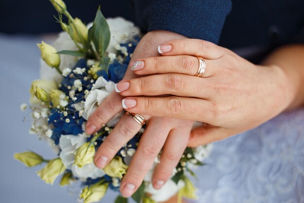 Nowożeńcy, panna młoda i pan młody trzymają ręce za bukiet kwiatów, bukiet ślubny.