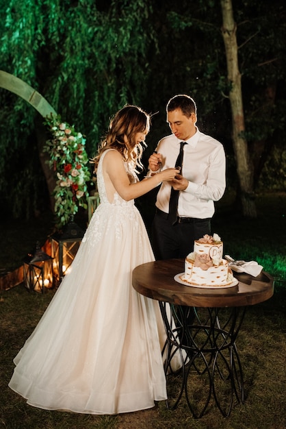Nowożeńcy radośnie kroją, śmieją się i smakują tort weselny