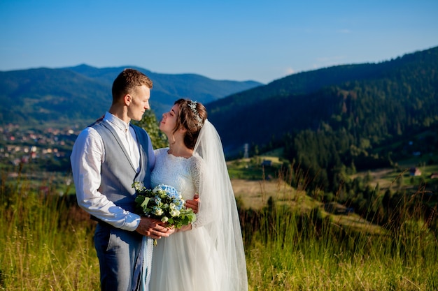 Nowożeńcy Uśmiechają Się I Przytulają Na łące Na Szczycie Góry