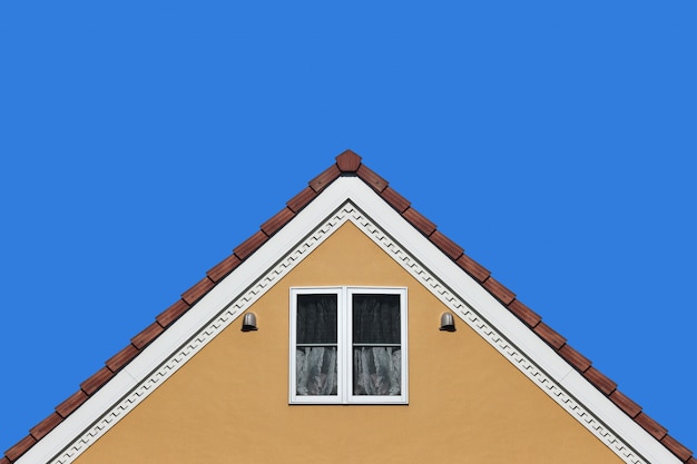 Nowożytna pomarańcze domu dachu dwuspadowego projekta ściana z jasnym niebieskiego nieba tłem.
