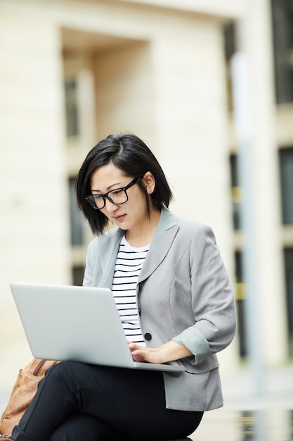 Nowożytny Azjatycki bizneswoman używa laptop Outdoors