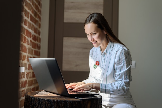 Nowożytny portret kobieta używa laptop indoors.