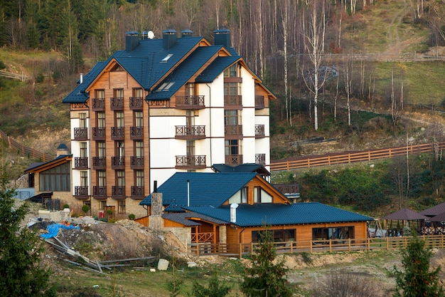 Zdjęcie nowy nowoczesny komfortowy czteropiętrowy budynek hotelowy z przyłączonymi lokalami, pokojami na poddaszu i wysokimi kominami na ekologicznym terenie wiejskim na świerku wiosną lub latem.