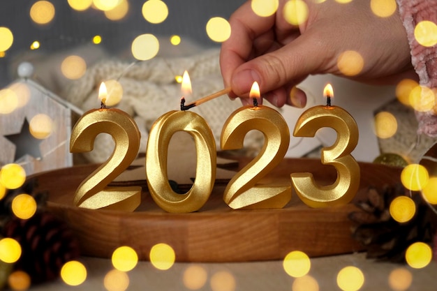 Nowy Rok 2023 Złote Cyfry Płoną Świece Zamazane Światła w tle Kartka Świąteczna Szczęśliwego Nowego Roku z Prezentami Ozdoby Kokardki i Konfetti Nowoczesna Świąteczna Kreatywna Kartka Z Życzeniami