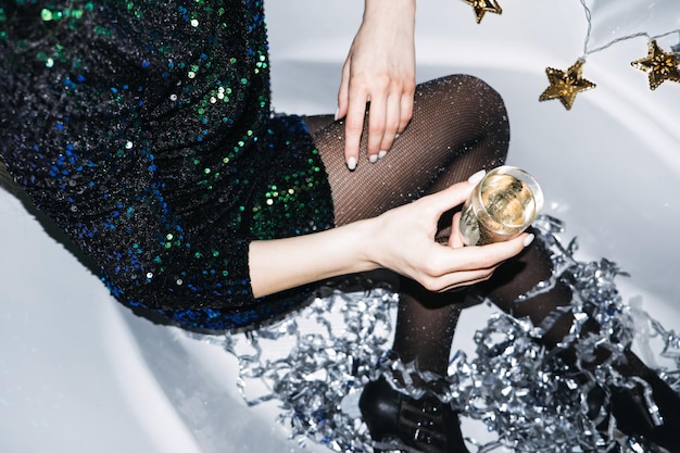 Nowy rok party celebracja szczęśliwa młoda kobieta w sukni wieczorowej siedzi w wannie i pije