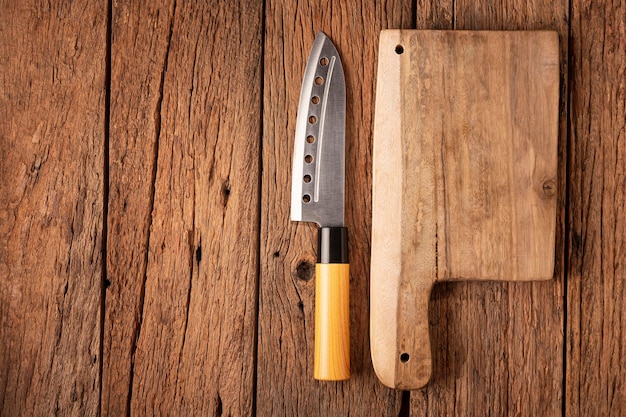 Nóż szefa kuchni i deska do krojenia na rustykalnym drewnianym stole.