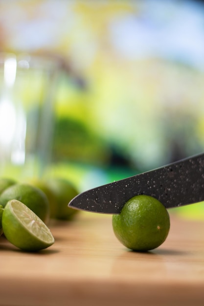 Zdjęcie nóż tnie limonkę na drewnianej desce do krojenia.