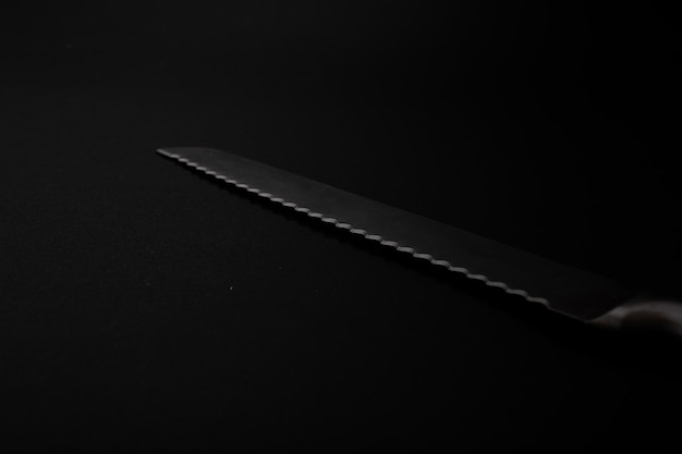 Noże wykonane z metalu w kolorze srebrnym leżą na czarnym tle z blaskiem światła