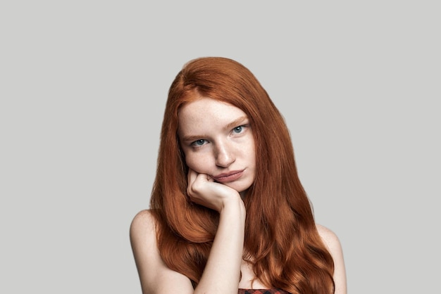 Nudny portret sfrustrowanej dziewczyny z rudymi włosami robi smutną minę, gdy stoi naprzeciw