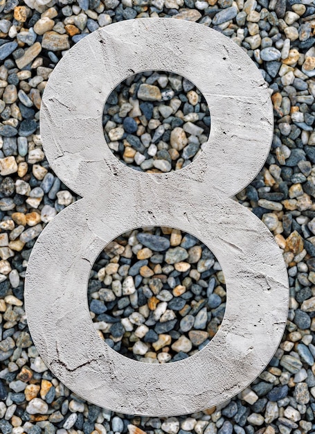 Numer 8 z betonową teksturą na tle kamieni