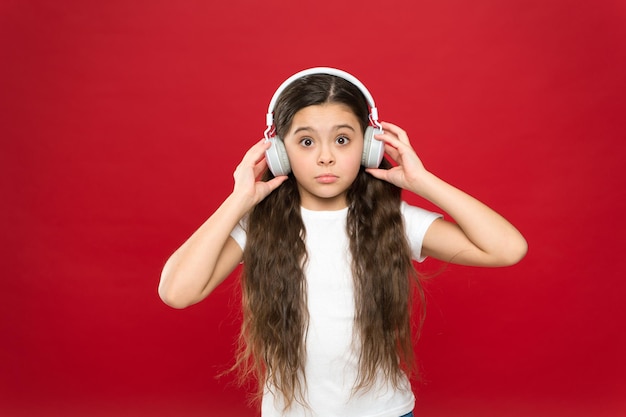 O co w tym wszystkim chodzi. Mała dziewczynka nosi słuchawki stereo. Fajny fan muzyki z bezprzewodowym zestawem słuchawkowym. Małe dziecko korzystające z technologii do wypoczynku lub edukacji. Mała dziewczynka słucha muzyki.