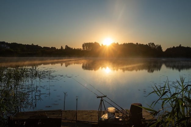 Zdjęcie o świcie na pomoście instalowane są dwie wędki do połowu ryb na jeziorze