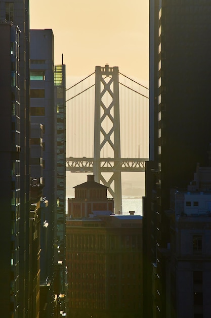 Zdjęcie oakland bay bridge w san francisco podczas złotej godziny między drapaczami chmur