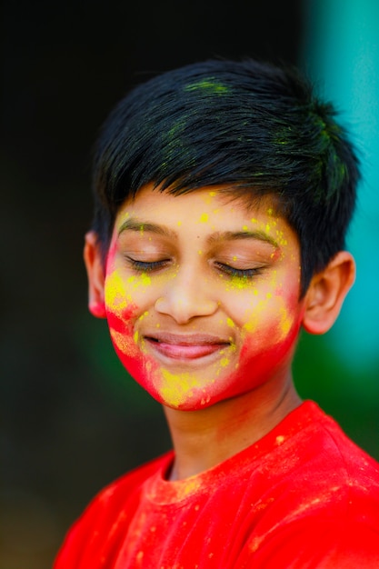 Obchody Holi -Indyjski mały chłopiec bawiący się w Holi i pokazujący wyraz twarzy.