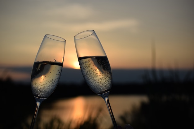 Obchody Nowego Roku dwoma kieliszkami wina o zachodzie słońca nad jeziorem z miejscem na tekst