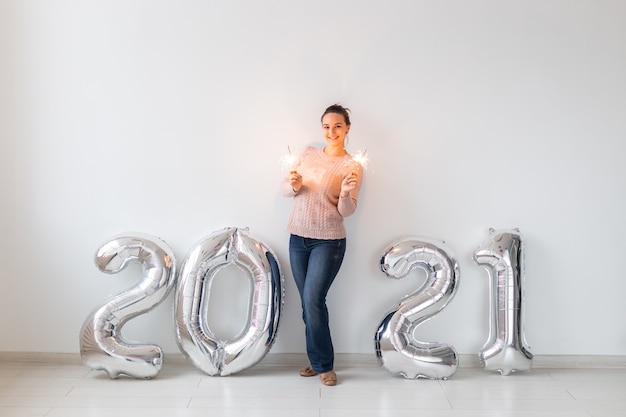 Obchody Nowego Roku i koncepcja partii - Szczęśliwa młoda kobieta z ognie w pobliżu srebrnych balonów 2021