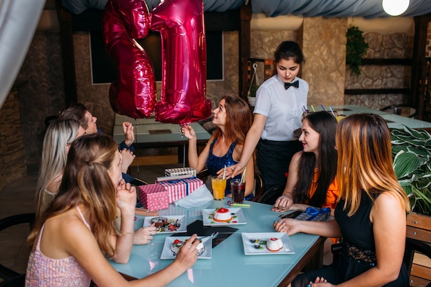 Zdjęcie obchody urodzin z przyjaciółmi. szczęśliwa firma młodzieżowa w kawiarni, nowoczesny czas wolny. radosny nastrój, praca kelnerki, koncepcja prawdziwego święta