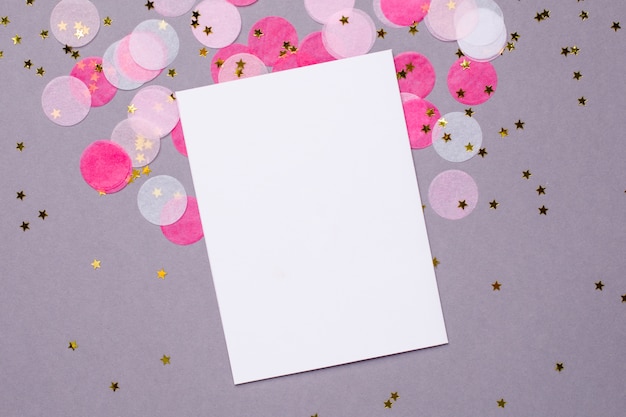 Zdjęcie obecna karta i różowe konfetti ze złotymi gwiazdkami na szaro