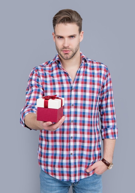 Obecna koncepcja sprzedaży mężczyzna trzyma prezent na sprzedaż na białym tle na szarym tle sprzedaż prezentu dla mężczyzny