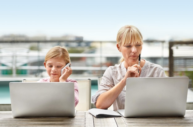 Obecne i przyszłe kobiety biznesu Ujęcie młodej dziewczyny i jej matki używających laptopów obok siebie