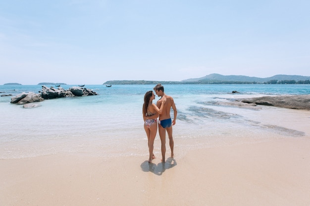 Obejmując romantyczną parę patrząc morze na wakacje na pięknej tropikalnej plaży. Morze krajobraz z tajlandzką łodzią. Phuket. Tajlandia. Widok z tyłu.