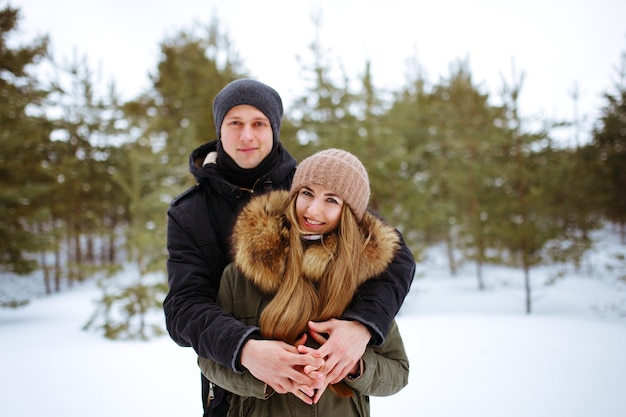 Obejmująca para patrząc na kamery z uśmiechem w winter park