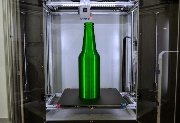Obiekt zielona butelka wydrukowana na zbliżeniu drukarki 3D na pulpicie drukarki 3d