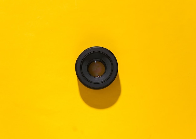 Obiektyw aparatu na żółtym jasnym tle z głębokim cieniem.
