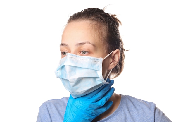 Objawy grypy. Kobieta w masce medycznej trzyma gardło na białym tle. Ból gardła.
