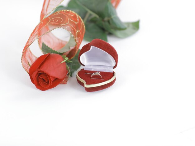 Obrączki ślubne i czerwona róża na białym tlezdjęcie z kopią s