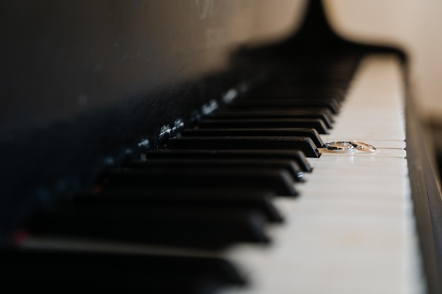 Obrączki ślubne leżą na klawiszach fortepianu