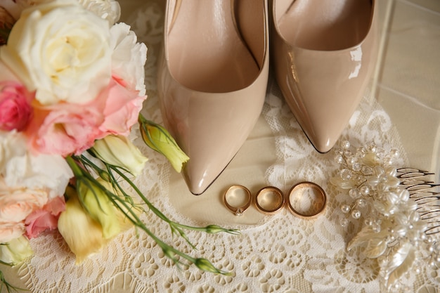 Obrączki ślubne w pobliżu buty ślubne na wysokich obcasach i bukiet ślubny