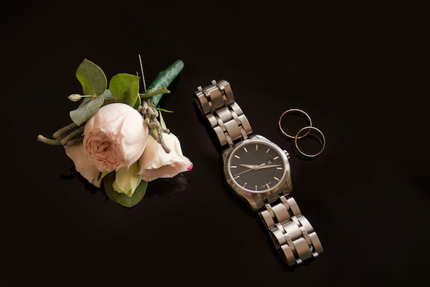 Zdjęcie obrączki ślubne z zegarkiem i różami
