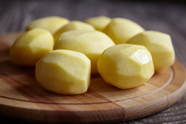 Obrane ziemniaki na drewnianej desce do krojenia na brązowy stół